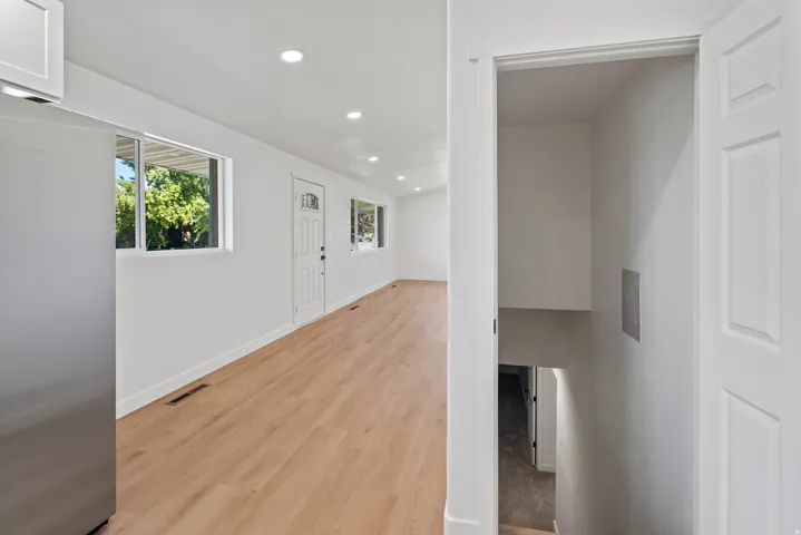 Wood-finish flooring, recessed lighting, and white walls throughout