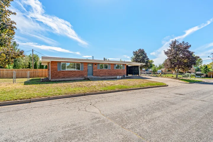Brick exterior with a covered carport, front yard, and fenced side yard