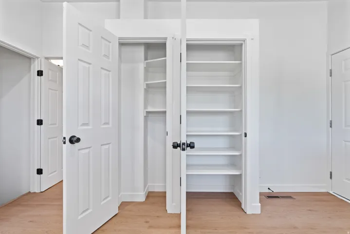 Built-in shelving, wood-finish flooring, white paneled doors, and matte black hardware