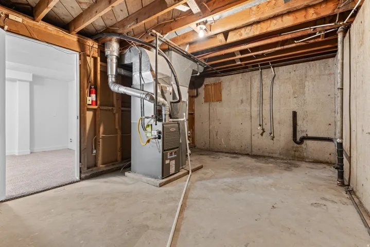 Concrete foundation walls and flooring, exposed ceiling joists, and a furnace system