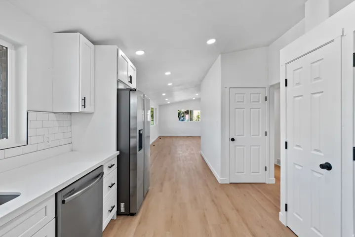 Kitchen with white cabinetry, stainless steel appliances, white subway tile backsplash, and light wood-finish flooring