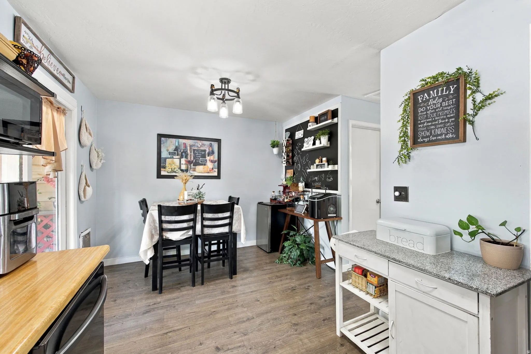 Wood-finish flooring, recessed lighting, and a chandelier illuminate the dining area