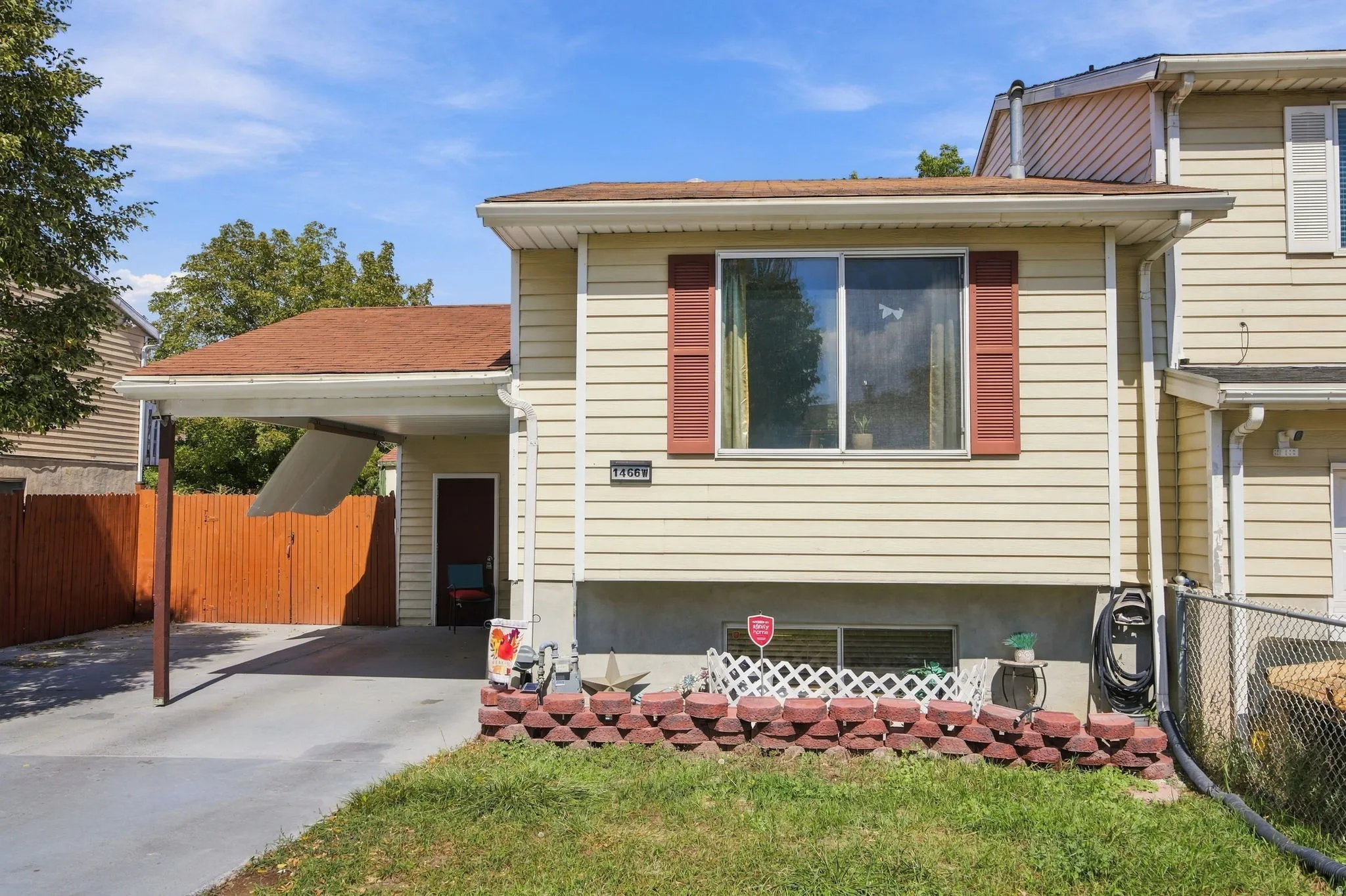 Exterior siding with red window shutters, carport, and a fenced yard