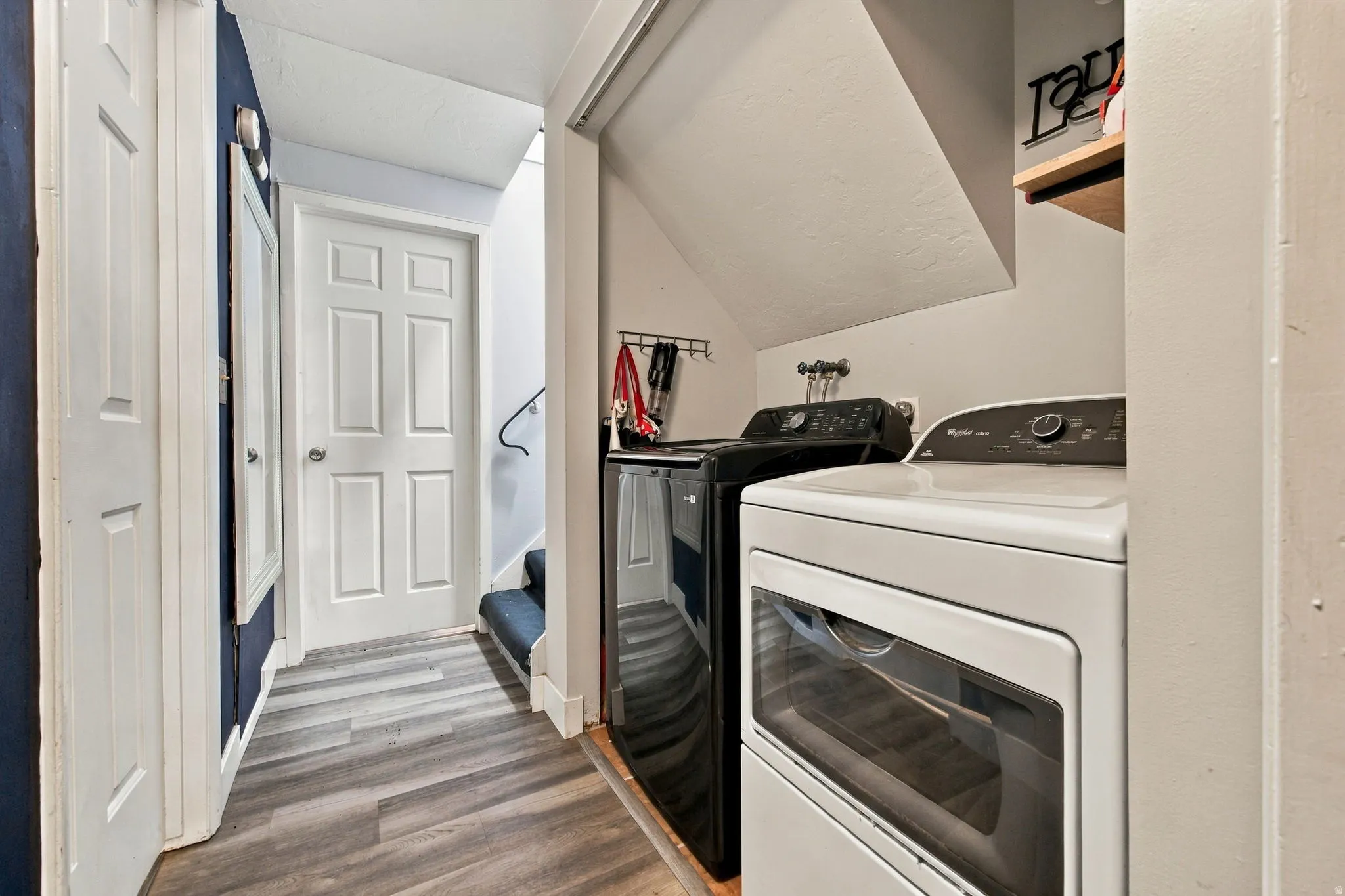 Dedicated laundry area with wood-finish flooring and integrated shelving