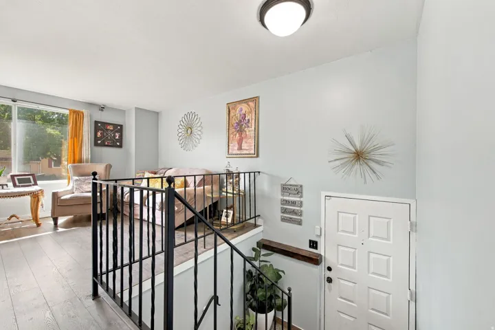 Wood-finish flooring throughout, with a white paneled entry door and a fixed overhead light fixture