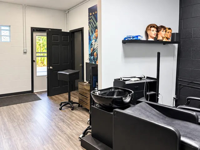 Wood-finish flooring, two black paneled doors, white painted block walls, black brick accent wall, and a fixed wall-mounted shelf