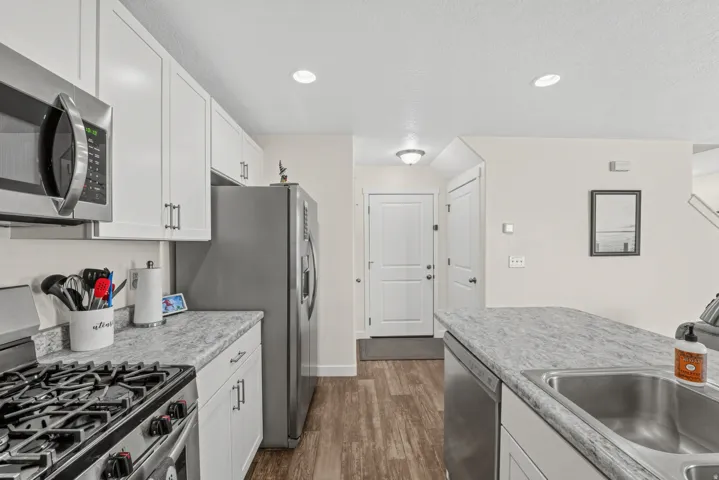 Kitchen featuring white cabinetry, stainless steel appliances, a gas range, and wood-finish flooring