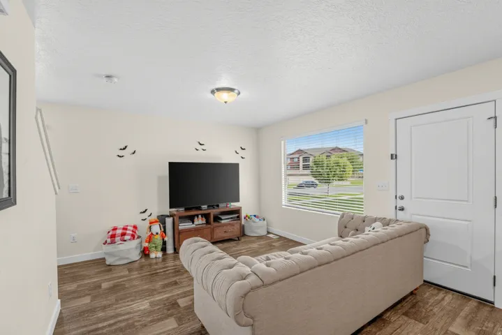 Wood-finish flooring throughout, light-colored walls, and a prominent window with blinds