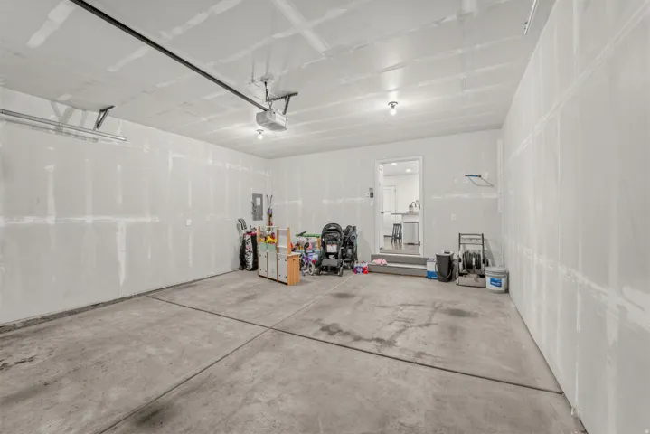 Concrete flooring, exposed ceiling joists, overhead lighting, garage door opener