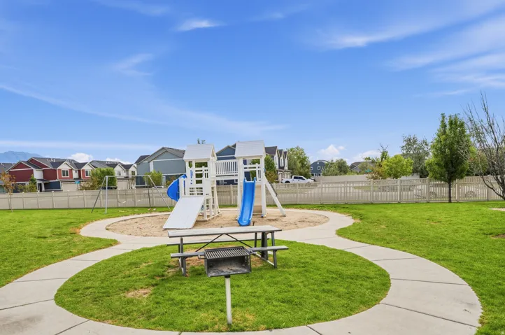 Community playground featuring a playset with slides, swings, and sandbox area