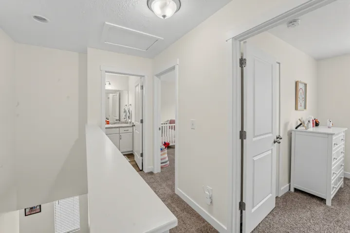 Upper level hallway with neutral wall paint and carpeted flooring