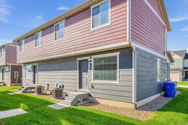 Two-story exterior with multi-toned siding, concrete patios, and manicured green space