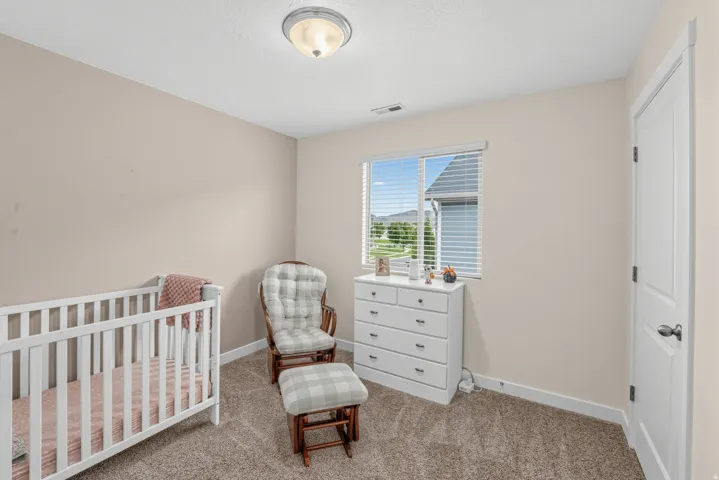 Soft neutral-toned walls complement the textured carpet flooring