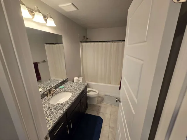 Vanity with a polished stone countertop, undermount sink, and dark wood-finish cabinetry