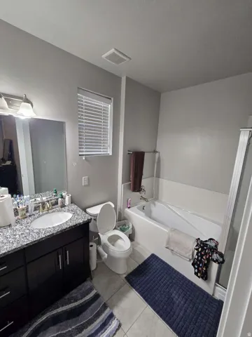 Granite-finish countertop with an undermount sink, dark wood-finish vanity, and a built-in bathtub