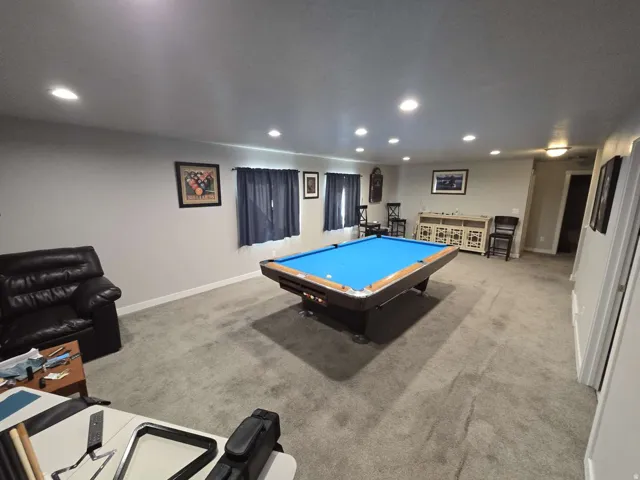 Recessed lighting illuminates a spacious room featuring wall-to-wall carpeting and neutral wall tones