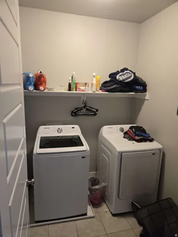 Laundry area featuring a built-in shelf, neutral wall tones, and tiled flooring
