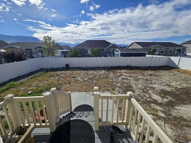 Expansive backyard space with a white privacy fence and concrete patio area