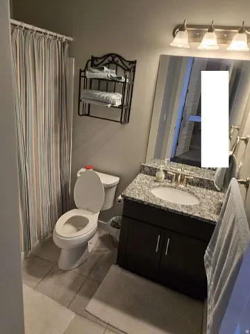 Dark wood-finish vanity with a granite-style countertop, undermount sink, and brushed nickel faucet