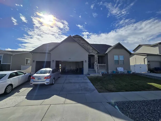 Stucco exterior with stone accents, covered front porch, attached two-car garage, and a concrete driveway