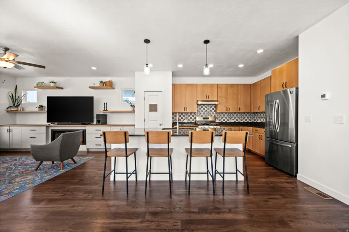 Hardwood-style flooring throughout, kitchen with wood cabinetry, stainless steel refrigerator, and patterned backsplash