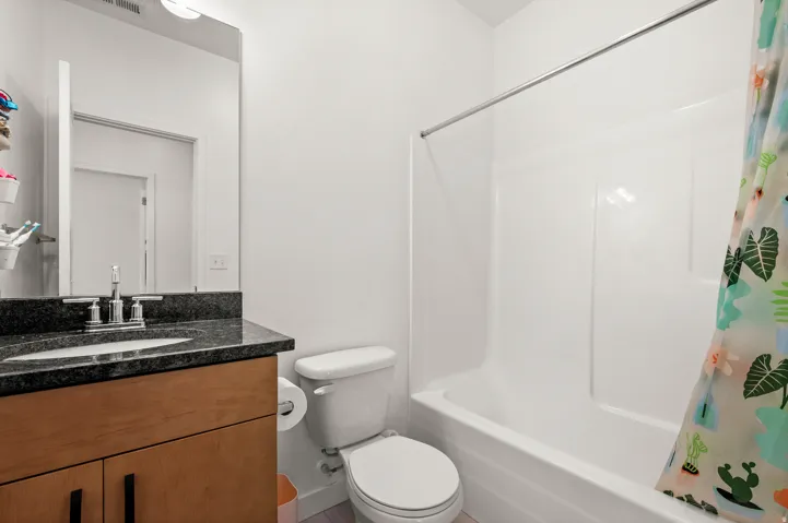 Bathroom featuring a vanity with dark countertop, undermount sink, and wood-finish cabinetry
