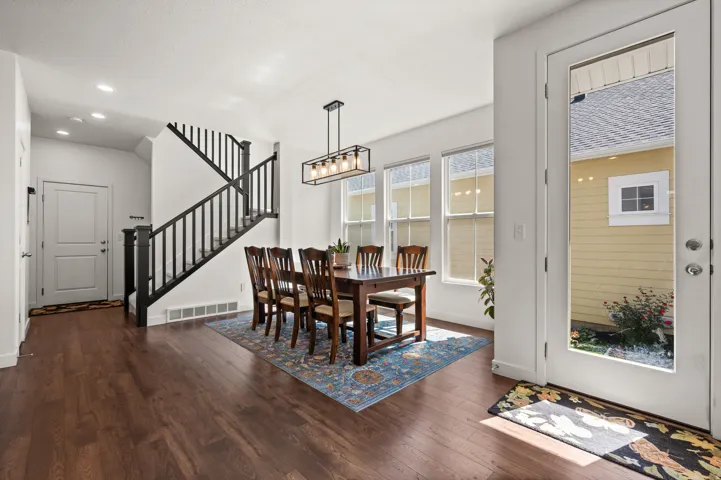 Hardwood-finish flooring throughout, framed glass door, multiple window set, recessed lighting, and a modern linear chandelier