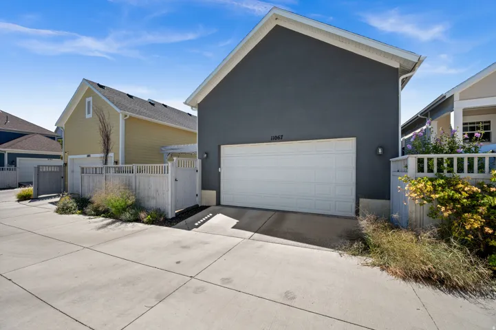 Attached two-car garage, concrete driveway, exterior wall sconce, and privacy fencing