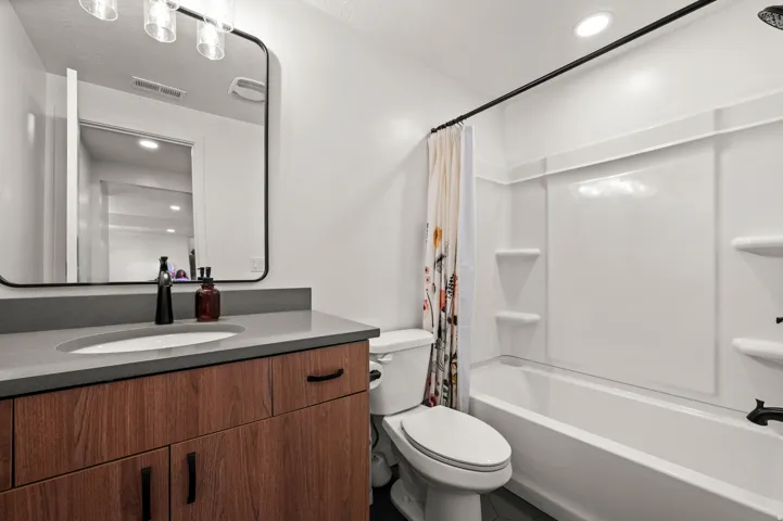 Modern vanity with wood-finish cabinetry, integrated sink, and dark countertop