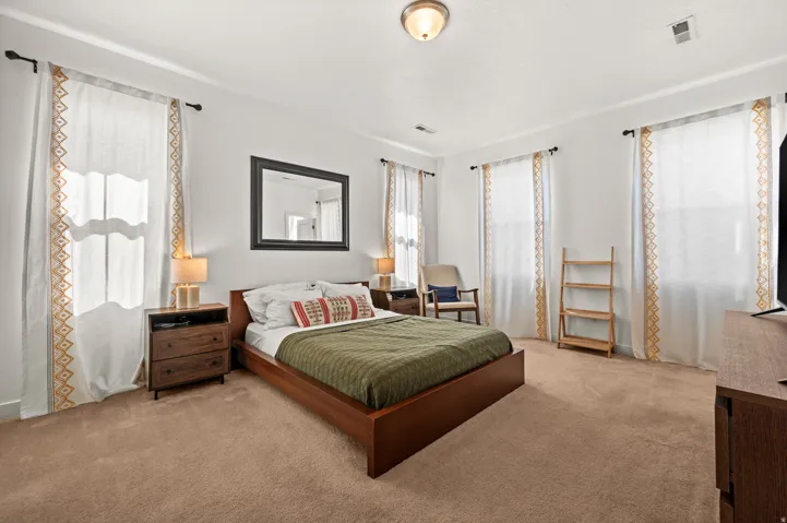 Carpeted bedroom with crown molding, a ceiling-mounted light fixture, and multiple windows
