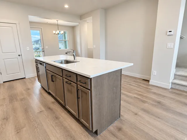 Kitchen island featuring a stainless steel sink, a stainless steel dishwasher, and cabinetry with dark hardware