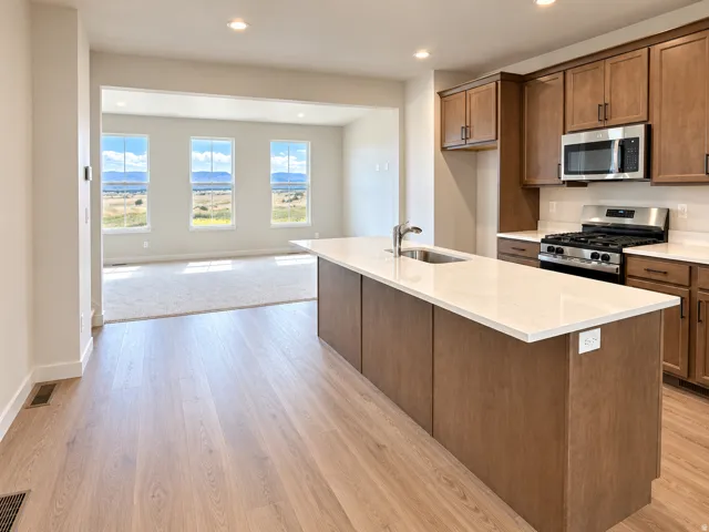 Kitchen featuring a large center island with a stainless steel sink, wood-finish cabinetry, and stainless steel appliances