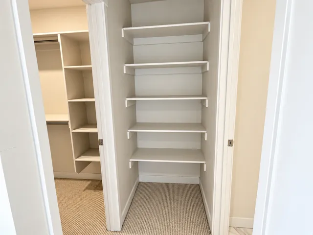 Primary walk in closet with additional storage shelves