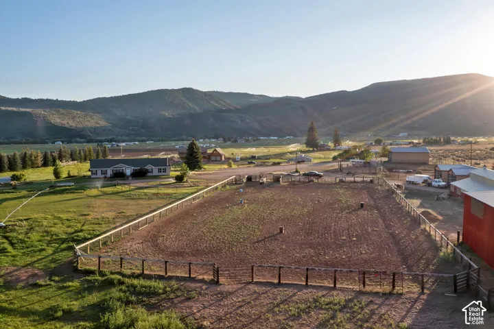 Expansive rural property featuring a fenced riding arena, a detached red barn, and a single-story residence
