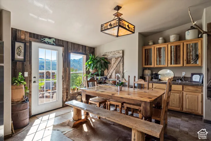 Floor-to-ceiling windows, reclaimed wood accent wall, wood-finish flooring, custom wood cabinetry with corrugated metal inserts, and built-in wet bar