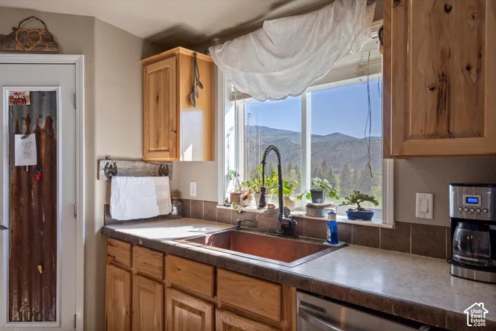 Kitchen with light wood cabinetry, a copper basin sink, and a black gooseneck faucet