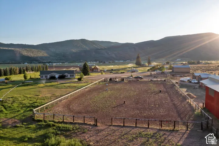 Expansive property featuring a large arena, multiple outbuildings, and a ranch-style residence, all surrounded by mountainous terrain