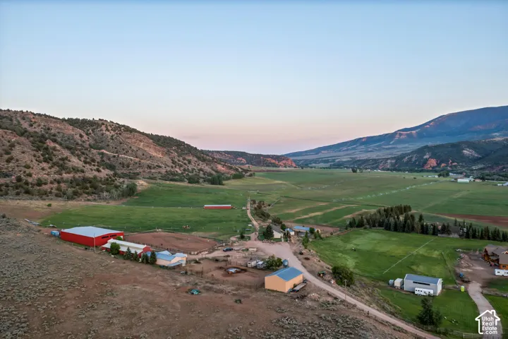 Expansive valley setting with green fields, surrounding hills, and multiple outbuildings