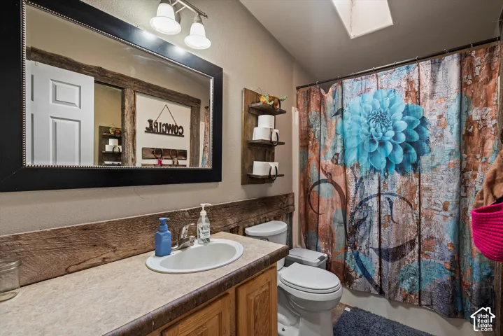 Vanity with a single sink and warm wood-finish cabinetry, illuminated by a multi-bulb light fixture