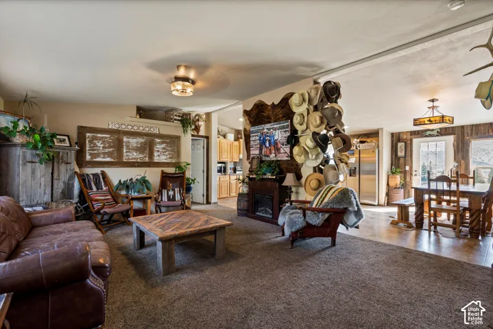 Carpeted living area with a built-in fireplace, wood-finish flooring, and a dining area with a chandelier