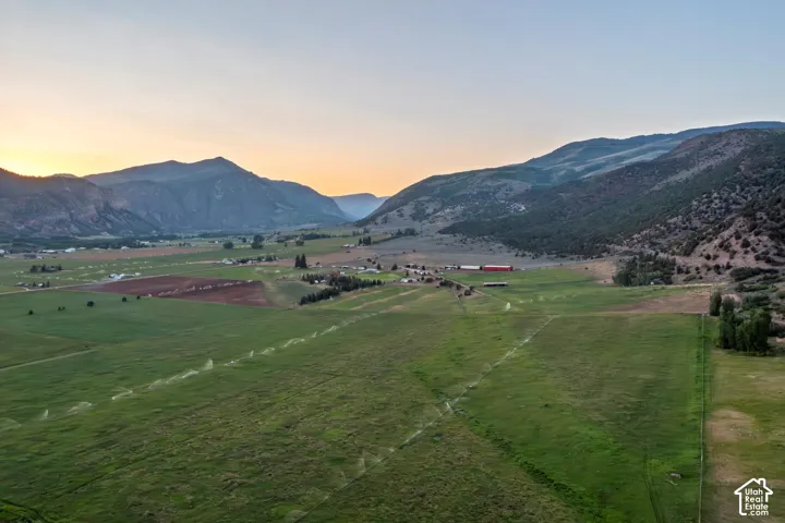 Expansive acreage featuring green fields, irrigation system, and surrounding mountainous terrain