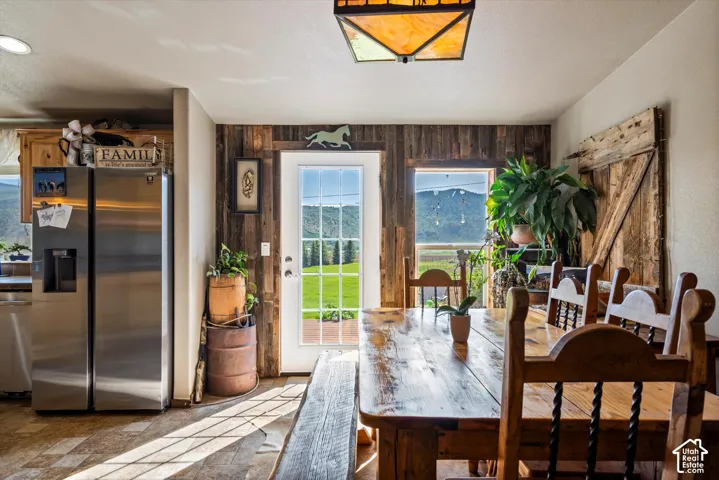 Wood-finish accent wall with a glass-paned door, large windows, and a wood-finish dining table