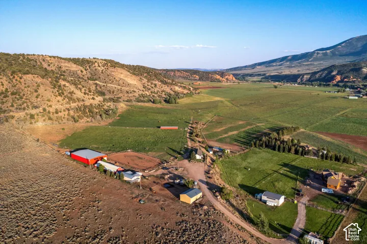 Expansive property featuring multiple structures, open fields, and surrounding natural landscapes