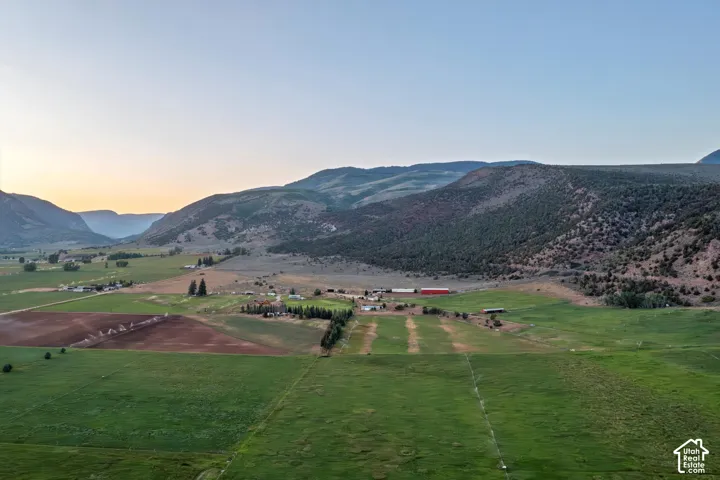 Expansive agricultural landscape with cultivated fields, verdant pastures, and distant mountain ranges