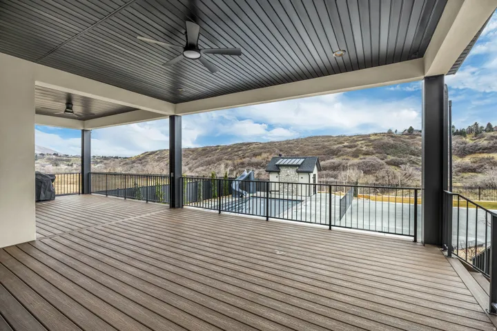 Expansive covered deck featuring wood-finish flooring and black metal railings
