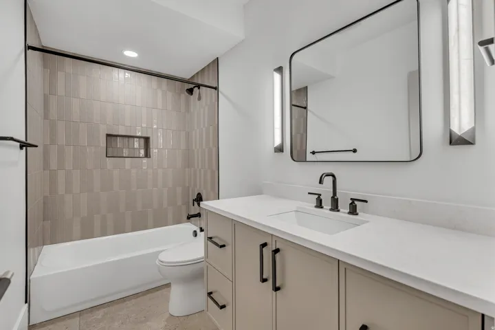 Bathroom featuring a neutral vanity with black hardware, an undermount sink, and a white countertop