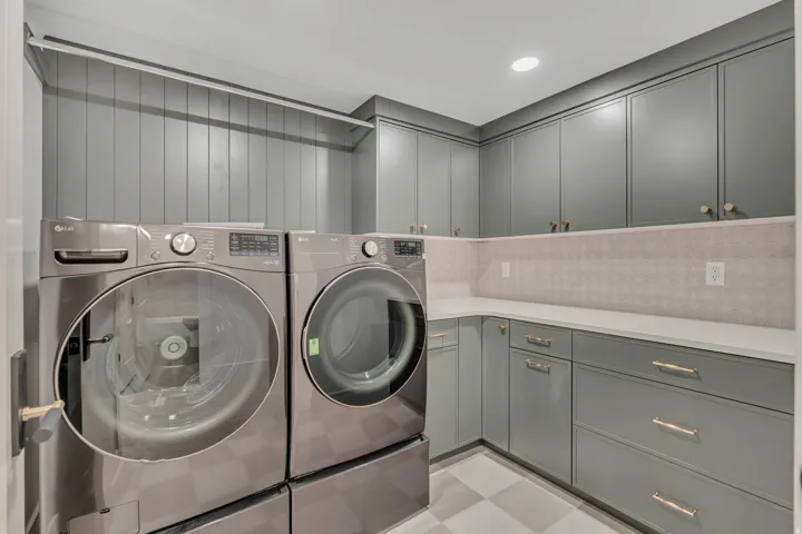 Laundry room featuring built-in cabinetry, solid surface countertops, a patterned backsplash, and recessed lighting