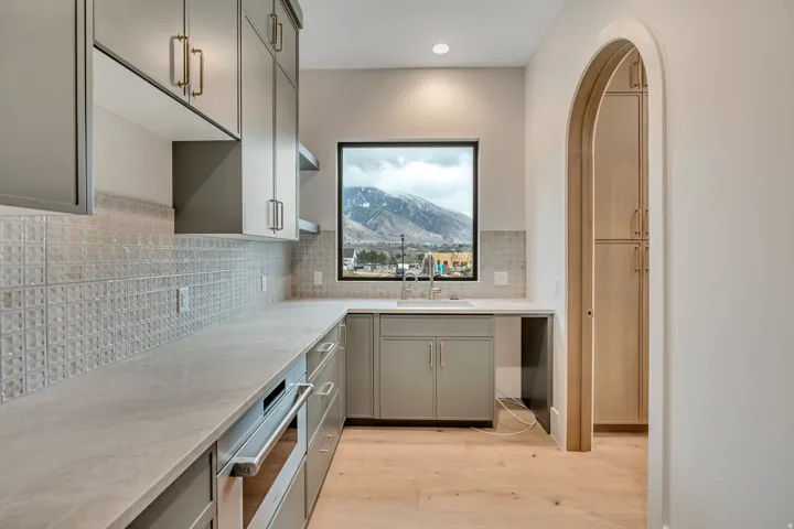 Contemporary kitchen with extensive countertop space, light-toned wood-finish flooring, a stainless steel sink, and built-in cabinetry