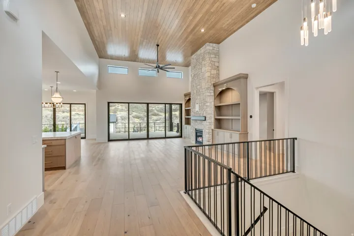 Vaulted wood-paneled ceiling, stone fireplace, built-in cabinetry, wood-finish flooring, and sliding glass doors