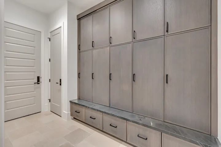 Built-in mudroom cabinetry with a stone countertop, featuring multiple storage compartments and integrated drawers